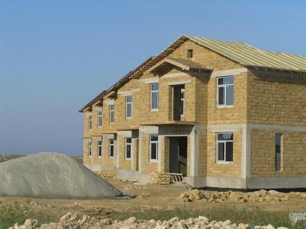 Снимката - къща с метална конструкция и стени бетон и фронтони от варовик.